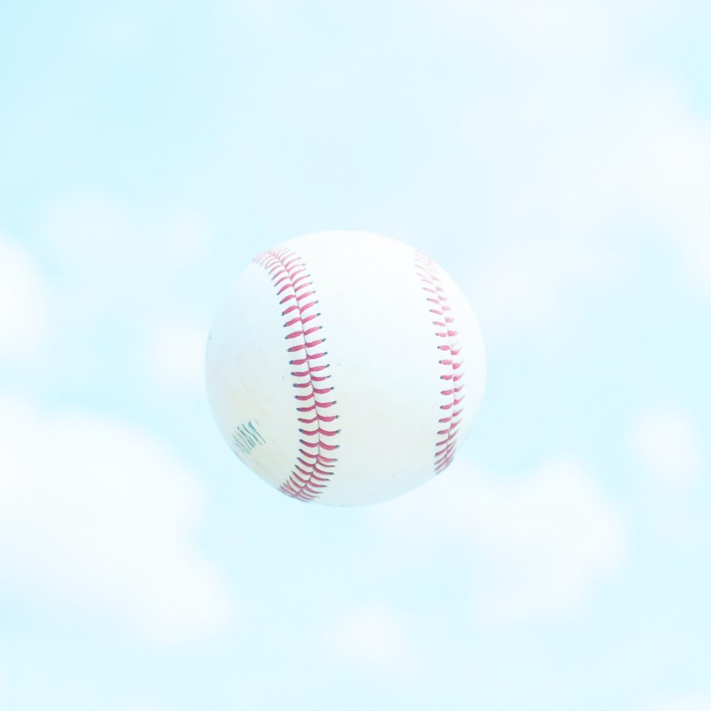 Bright airy outdoor baseball scene with soft sky-blue tones, calm open field, and natural daylight creating a fresh, clinical yet welcoming mood.
