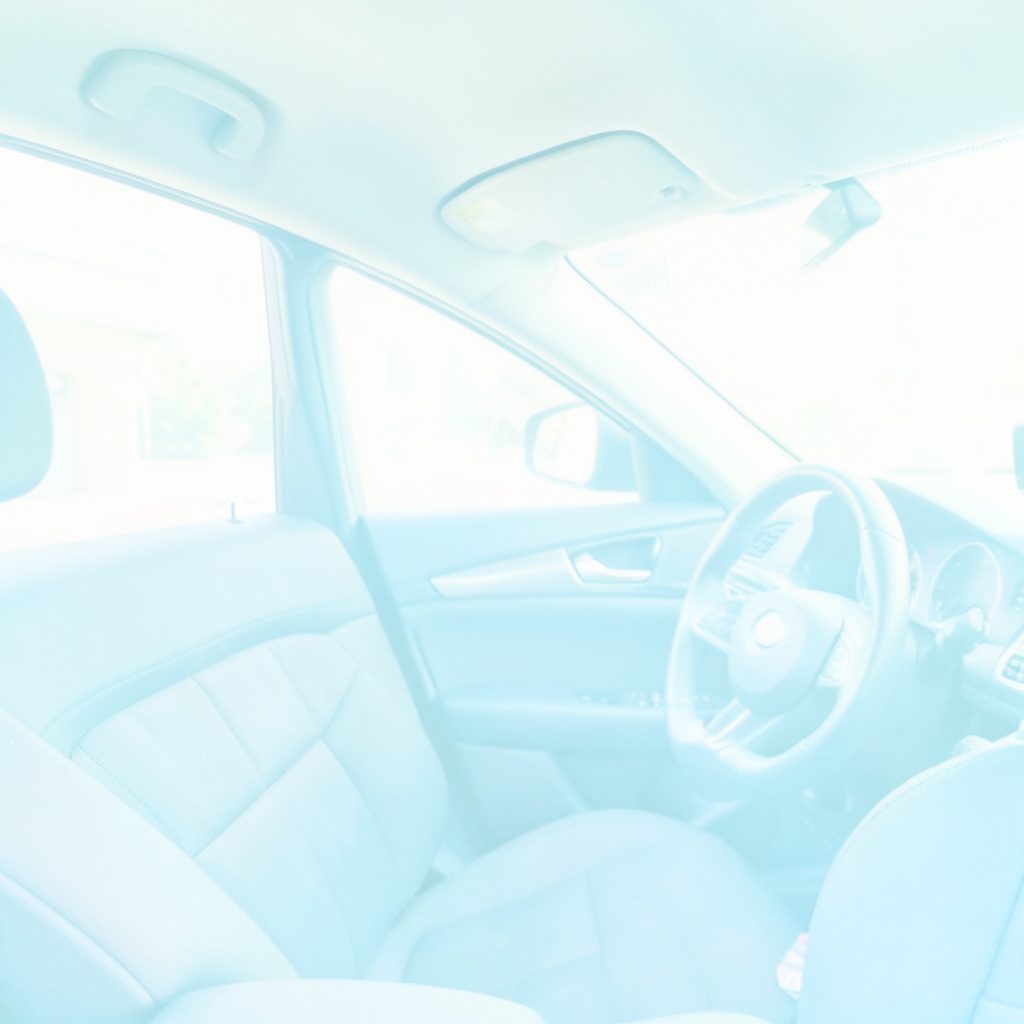A bright, airy high-key photograph of an open book resting on a car dashboard, soft daylight streaming through the windshield, pale blue and white tones, calm and focused mood